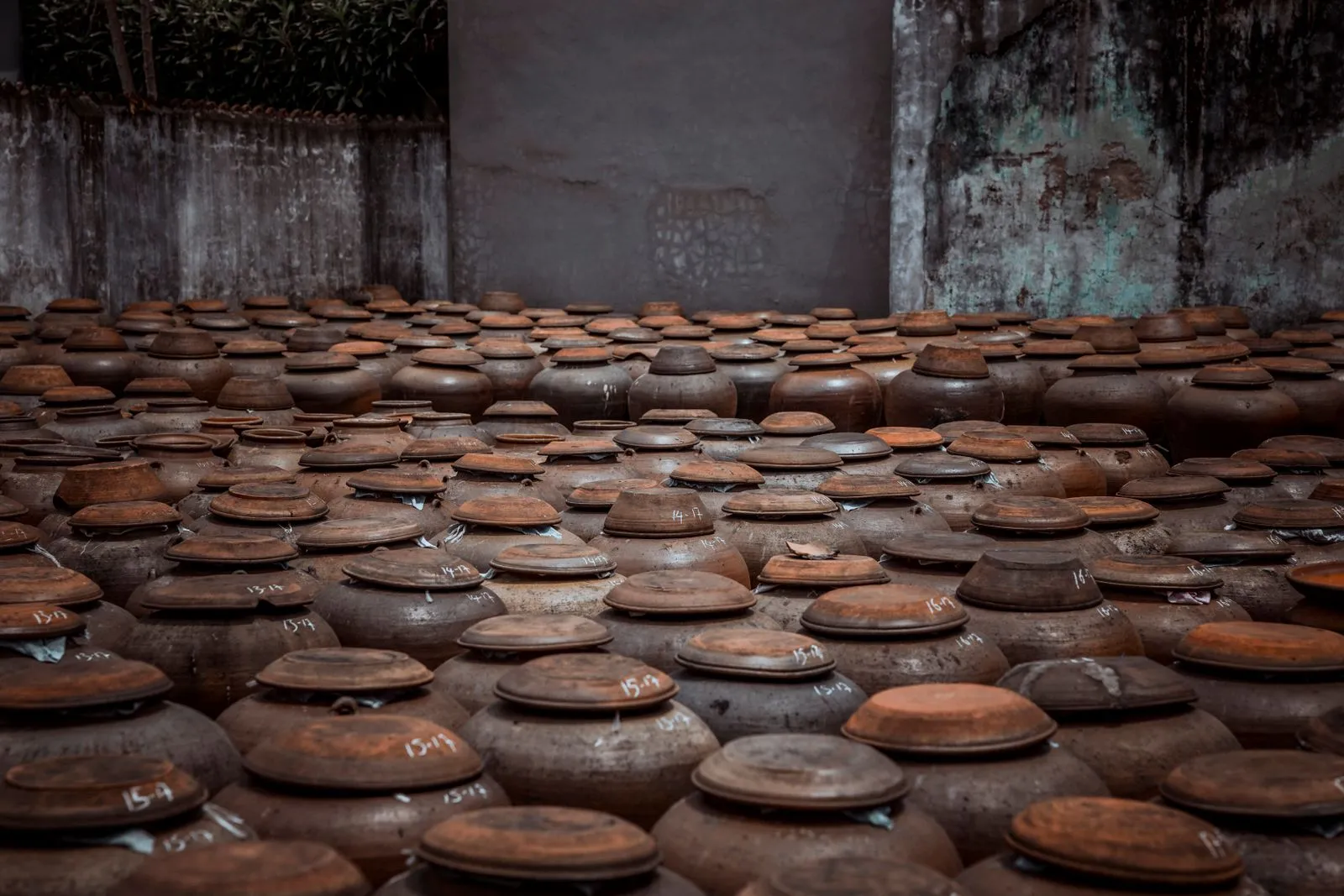 Overhead view of rustic pottery jars in a weathered indoor setting, showcasing handmade craftsmanship.